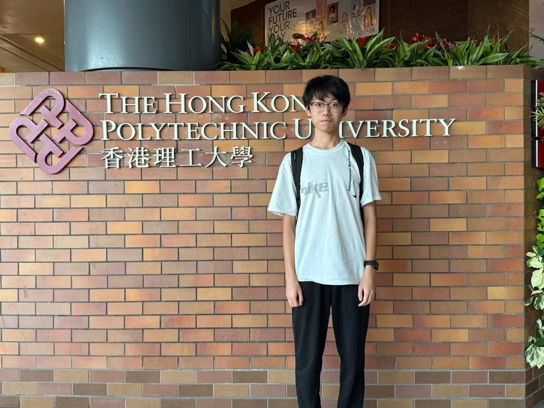August standing in front of The Hong Kong Polytechnic University sign